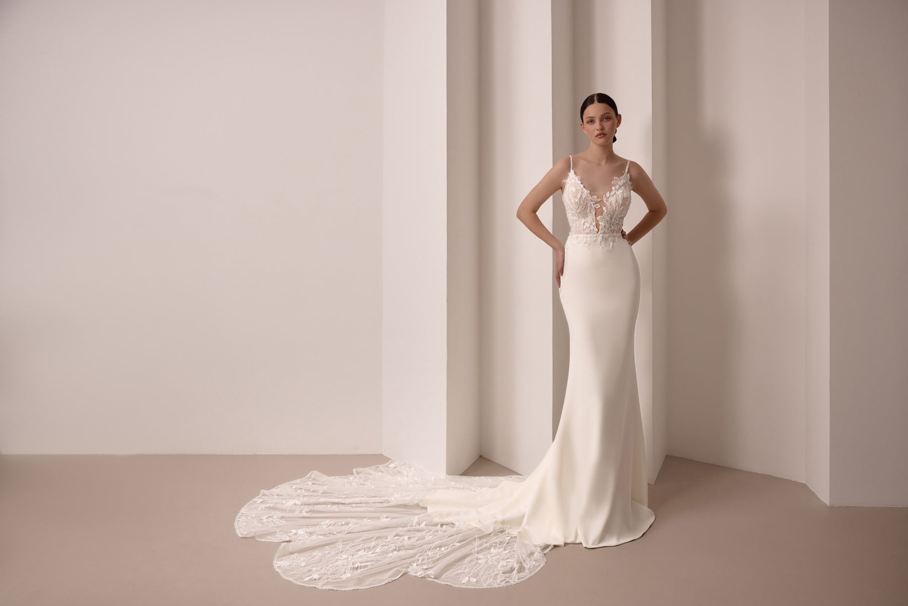 Fitted ivory wedding dress with floral lace bodice, thin straps, and a wide lace train