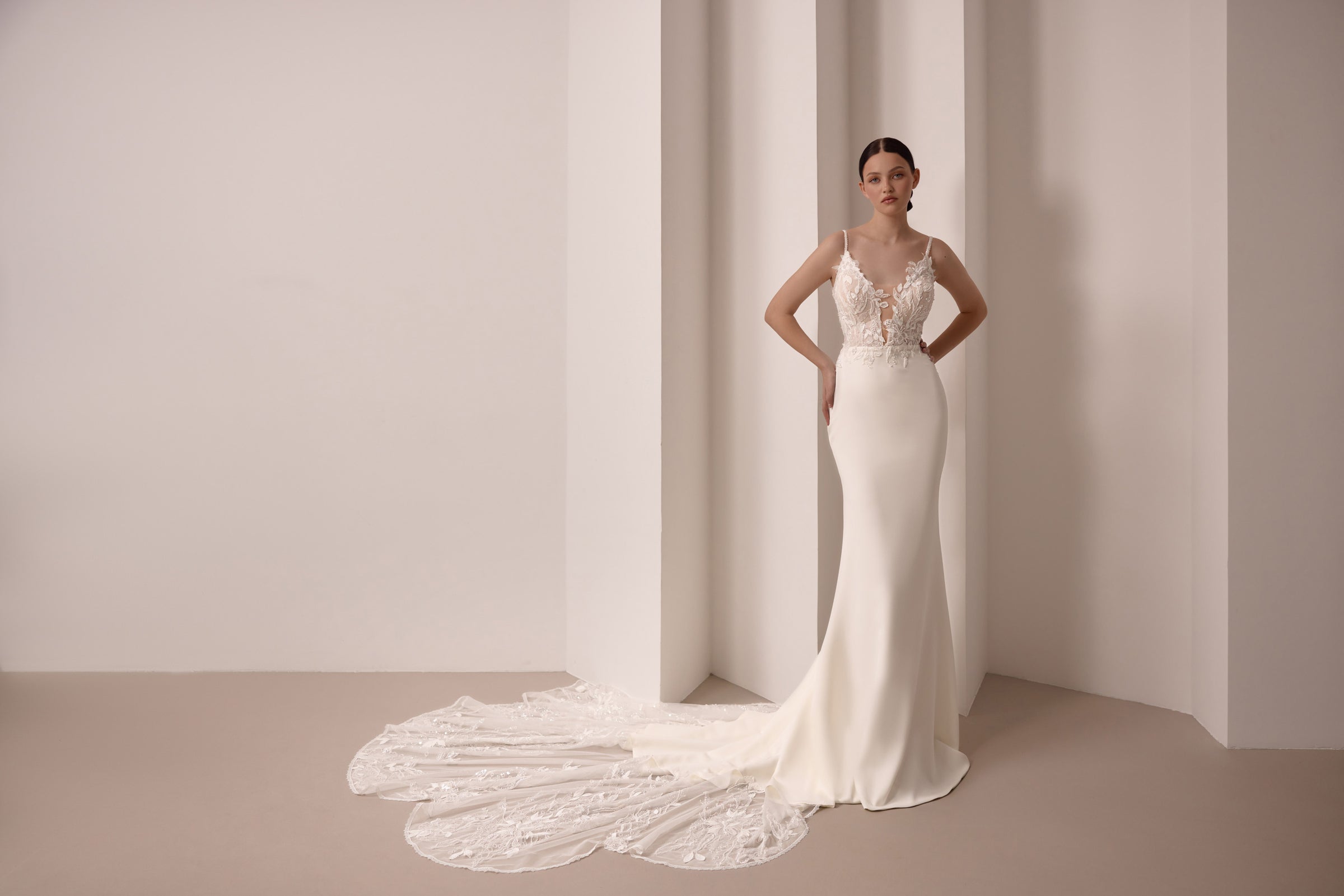 Fitted ivory wedding dress with floral lace bodice, thin straps, and a wide lace train