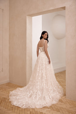 Ivory wedding dress with a corset-style back, thin straps, floral lace, and a long chapel train