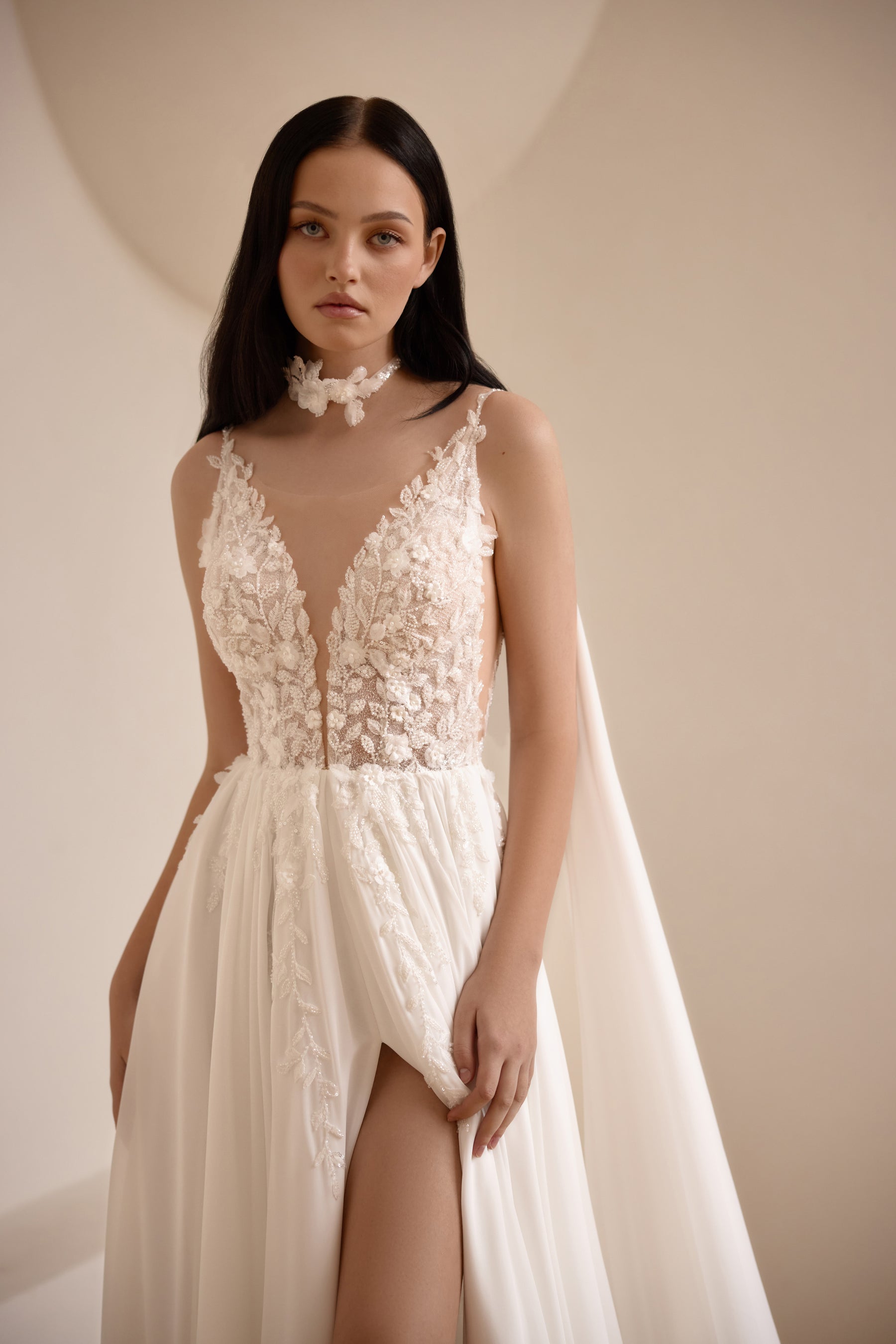 Close-up of an ivory wedding dress with sheer V-neck floral lace bodice and thigh-high skirt slit