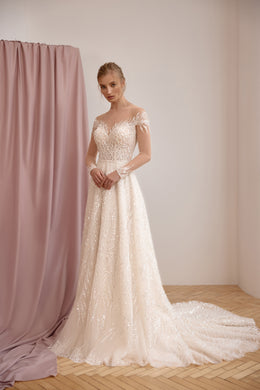 Ivory A-line wedding dress with an off-the-shoulder illusion neckline, shimmering lace, and a long train