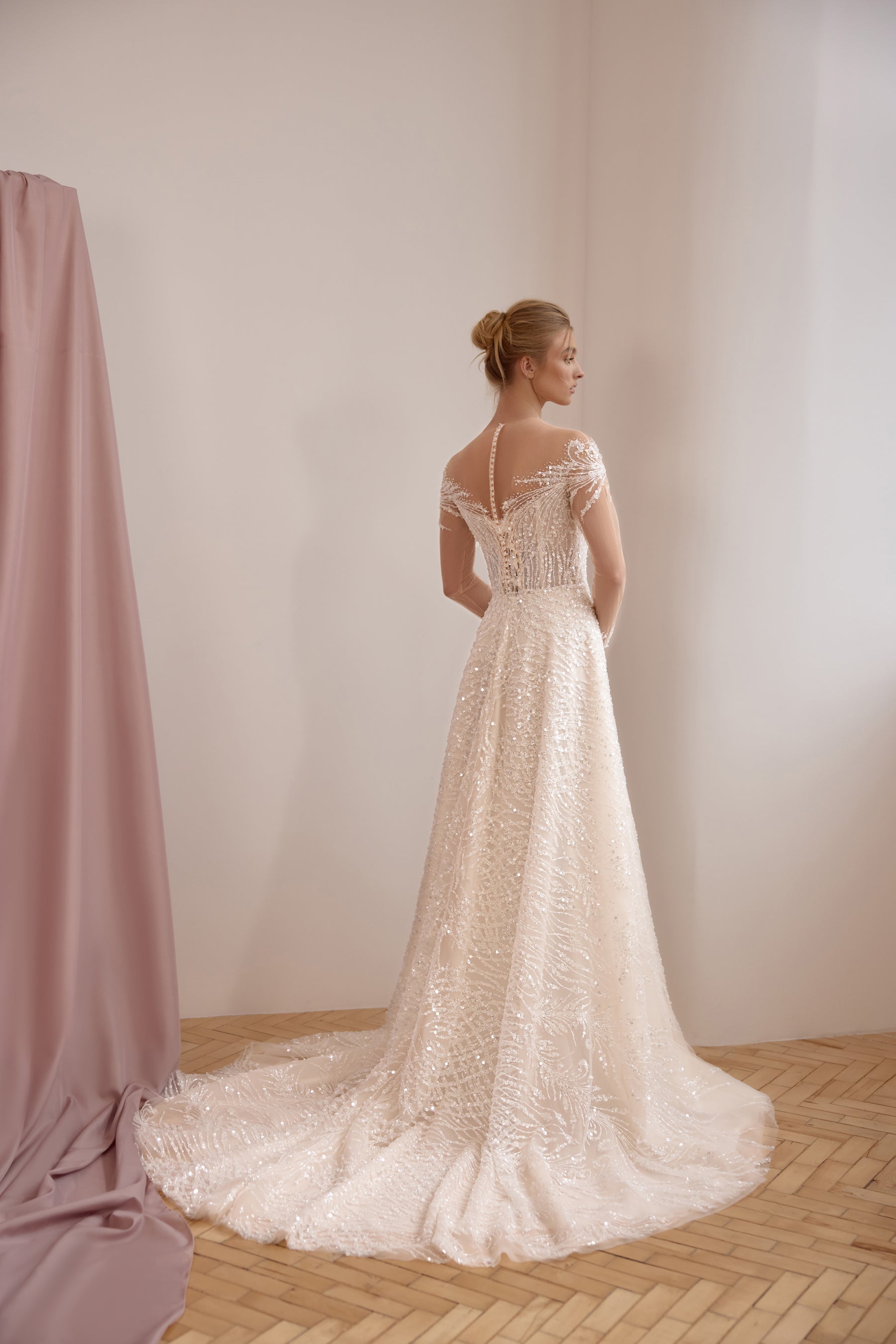 Ivory wedding dress showing a sheer lace back, short sleeves, A-line skirt, and a sweeping train