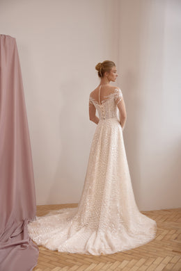 Ivory wedding dress showing a sheer lace back, short sleeves, A-line skirt, and a sweeping train