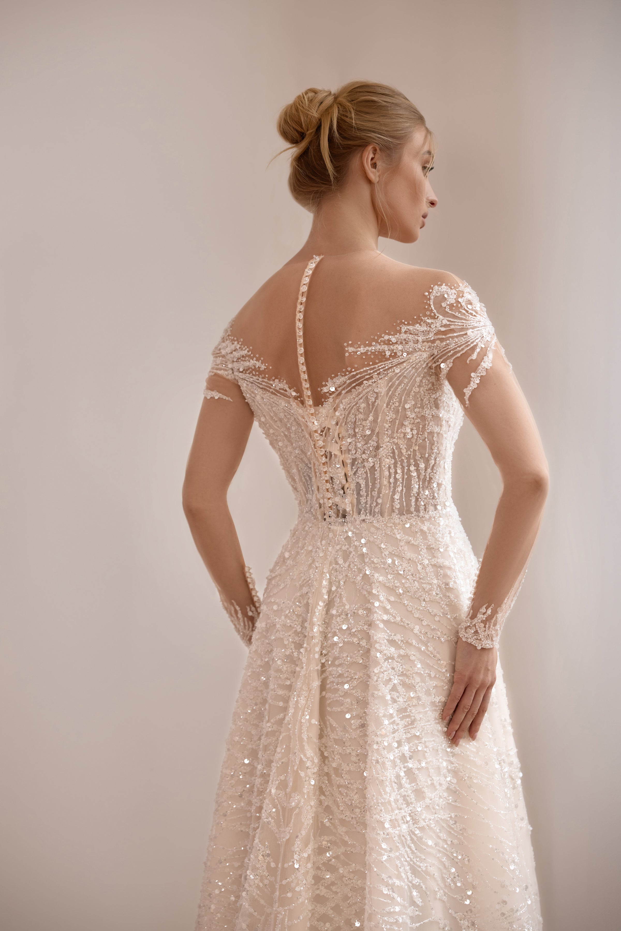 Detailed back of an ivory wedding dress with a sheer illusion panel, beaded lace, and a narrow center closure