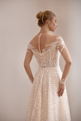 Detailed back of an ivory wedding dress with a sheer illusion panel, beaded lace, and a narrow center closure