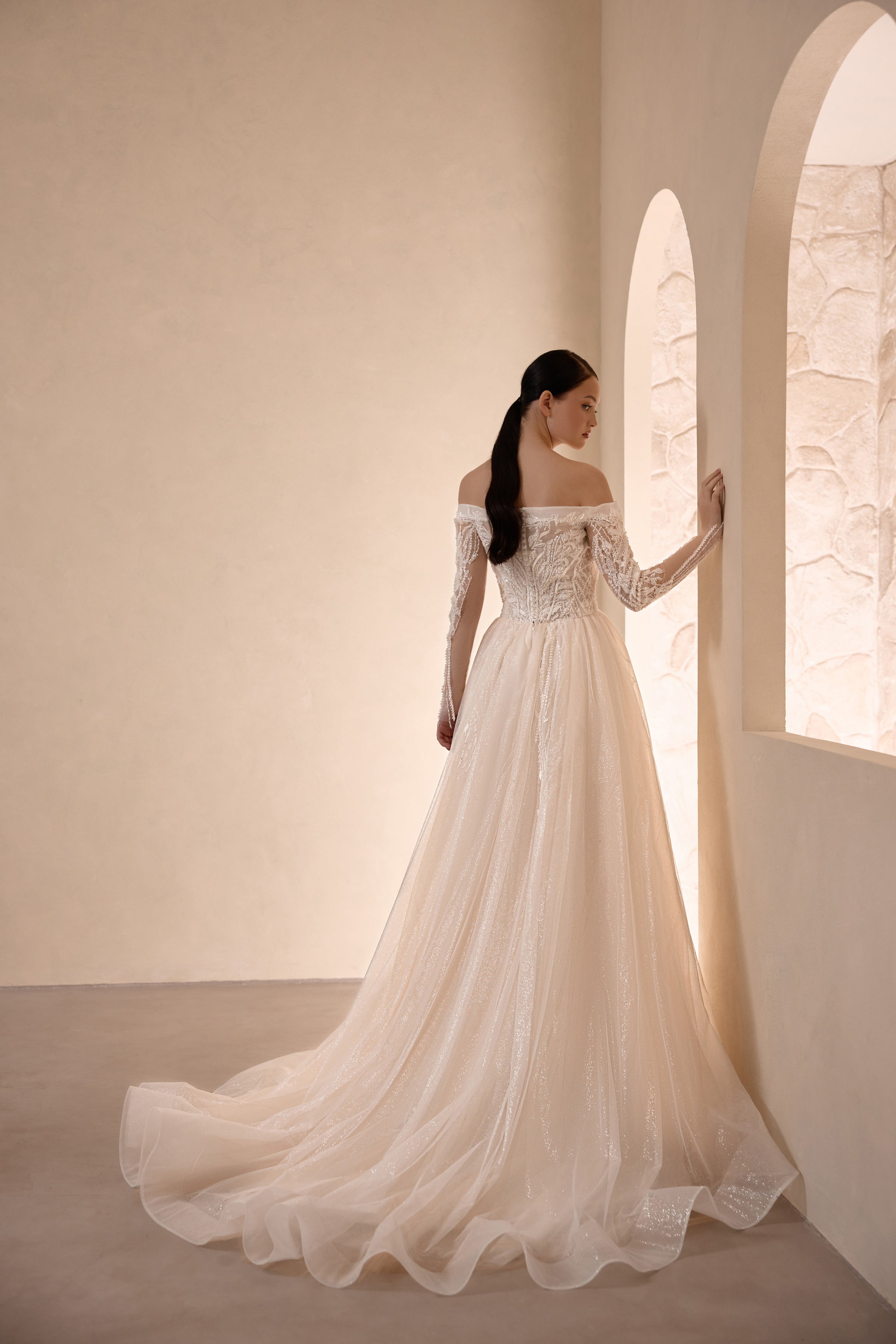 Ivory wedding dress with a beaded off-the-shoulder back, long sleeves, and sweeping train
