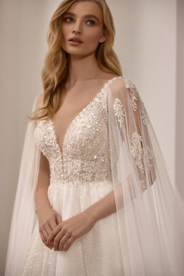 Close-up of a beaded V-neck bodice and sheer glitter sleeves on an ivory wedding dress