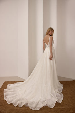 Open low back with thin straps and a long scalloped train on a sparkling ivory wedding dress