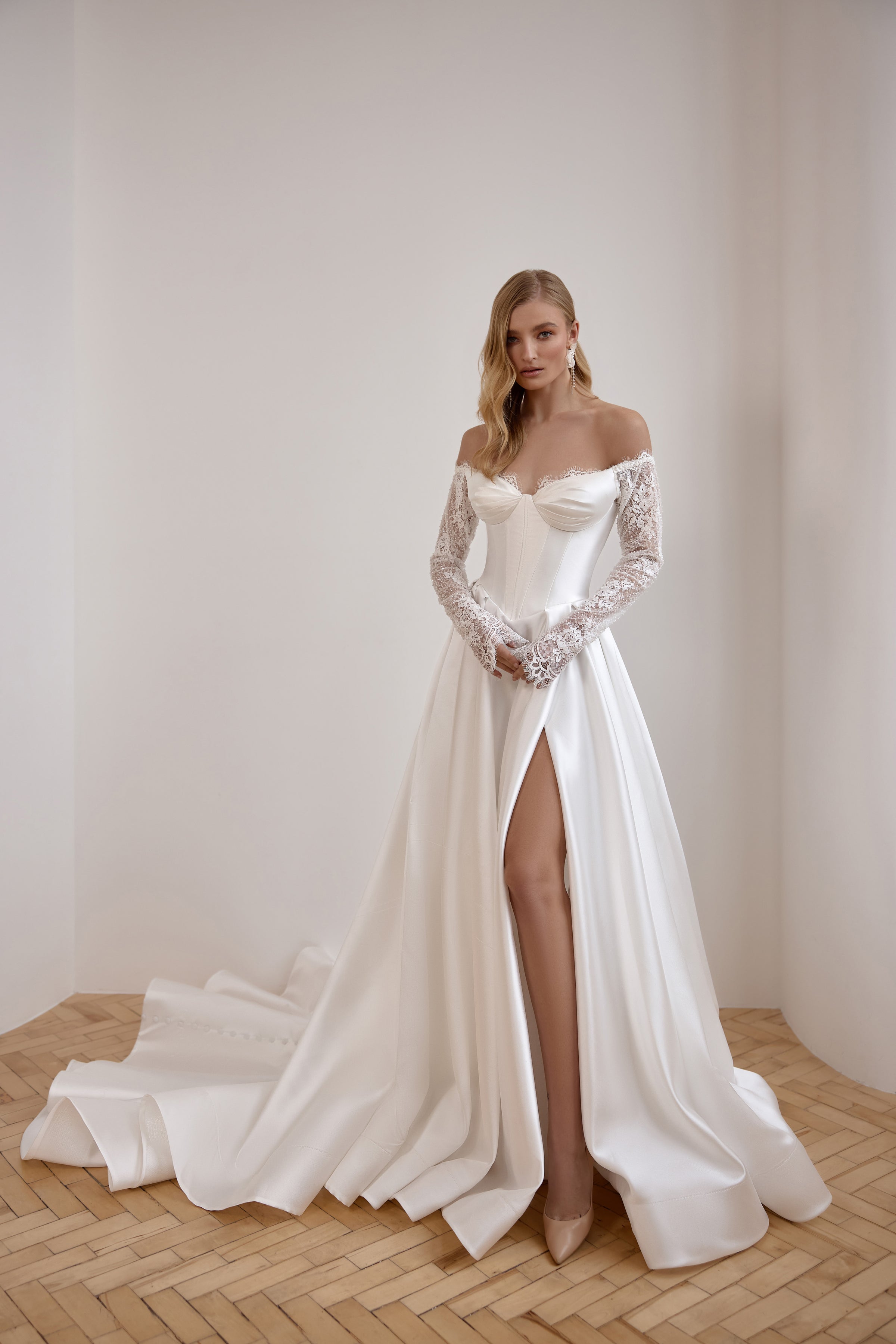 Ivory wedding dress with an off-the-shoulder neckline, lace sleeves, thigh-high slit, and long train
