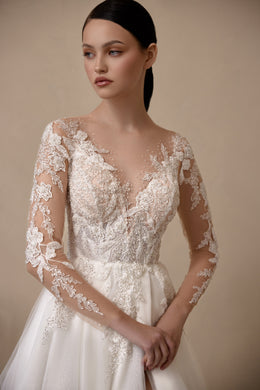 Close-up of floral lace appliqués on the illusion neckline, bodice, and sheer sleeves of an ivory wedding dress