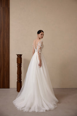 Back view of an ivory wedding dress with lace shoulder details, a flowing A-line skirt, and a long train
