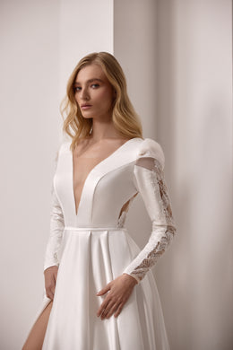 Ivory wedding dress with a plunging V-neckline, fitted lace sleeves, and a satin A-line skirt with slit