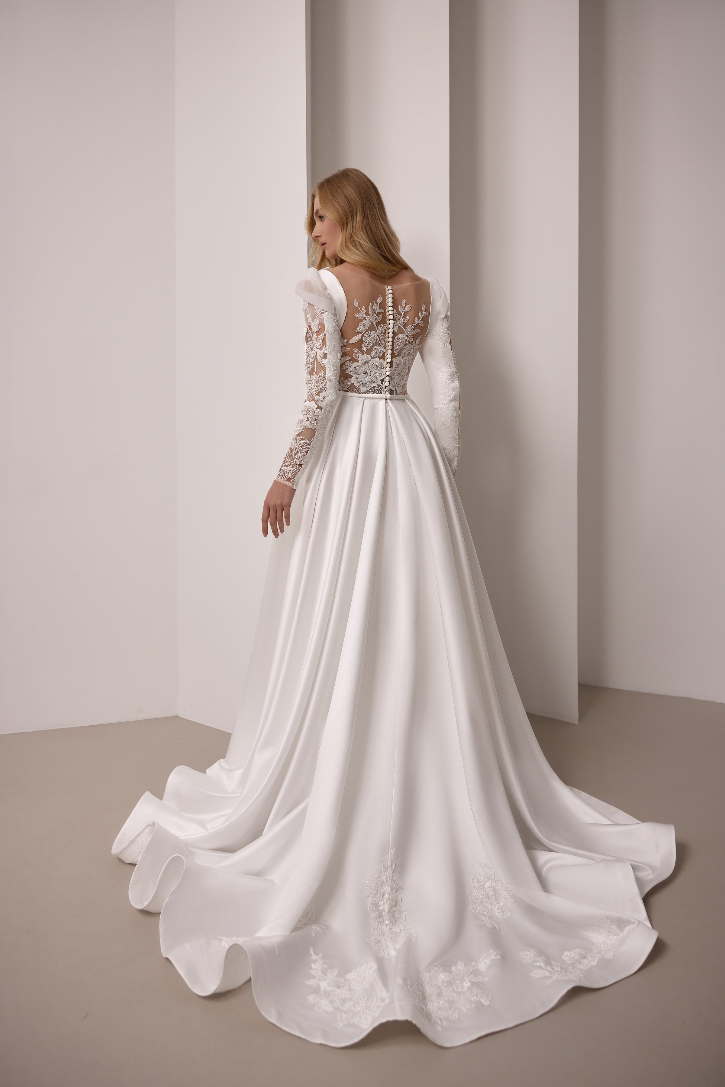 Sheer lace back and long flowing train with floral appliqués on an ivory wedding dress