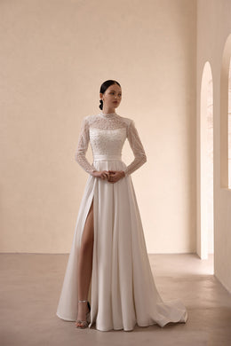 Ivory A-line wedding dress with a high beaded neckline, long sleeves, waist sash, and thigh-high slit