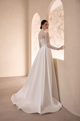 Back view of an ivory wedding dress with a beaded long-sleeve bodice and sweeping satin train