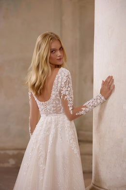 Ivory wedding dress with a low open back, long sheer floral-lace sleeves, and a sparkling A-line skirt