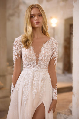 Close-up of an ivory wedding dress with a plunging V-neck, floral lace sleeves, and a front slit