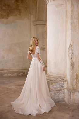 Ivory wedding dress shown from the back with a low lace-trimmed back, long sleeves, and a sweeping train