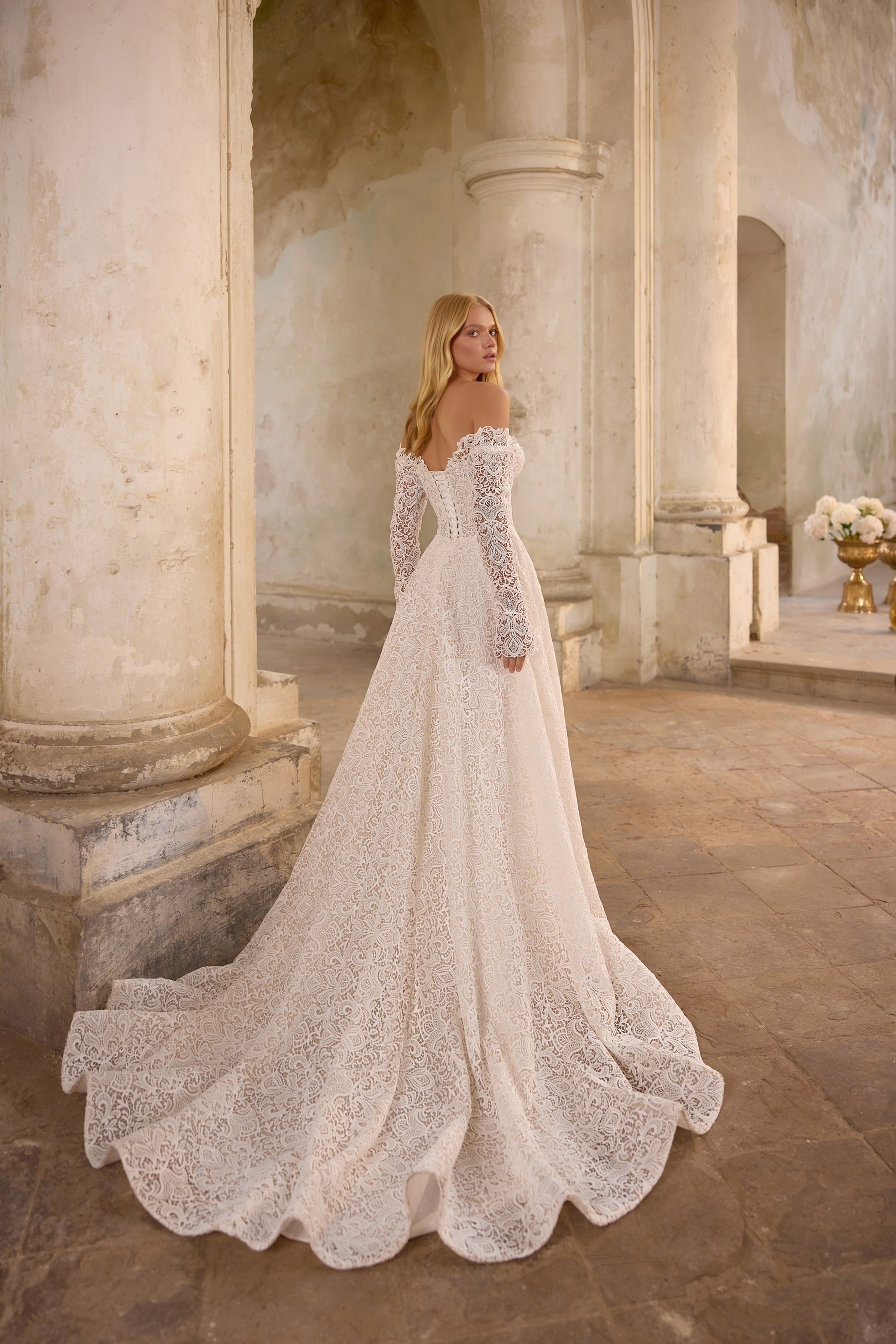 Lace wedding dress shown from the rear with long sleeves, an A-line skirt, and a wide scalloped train
