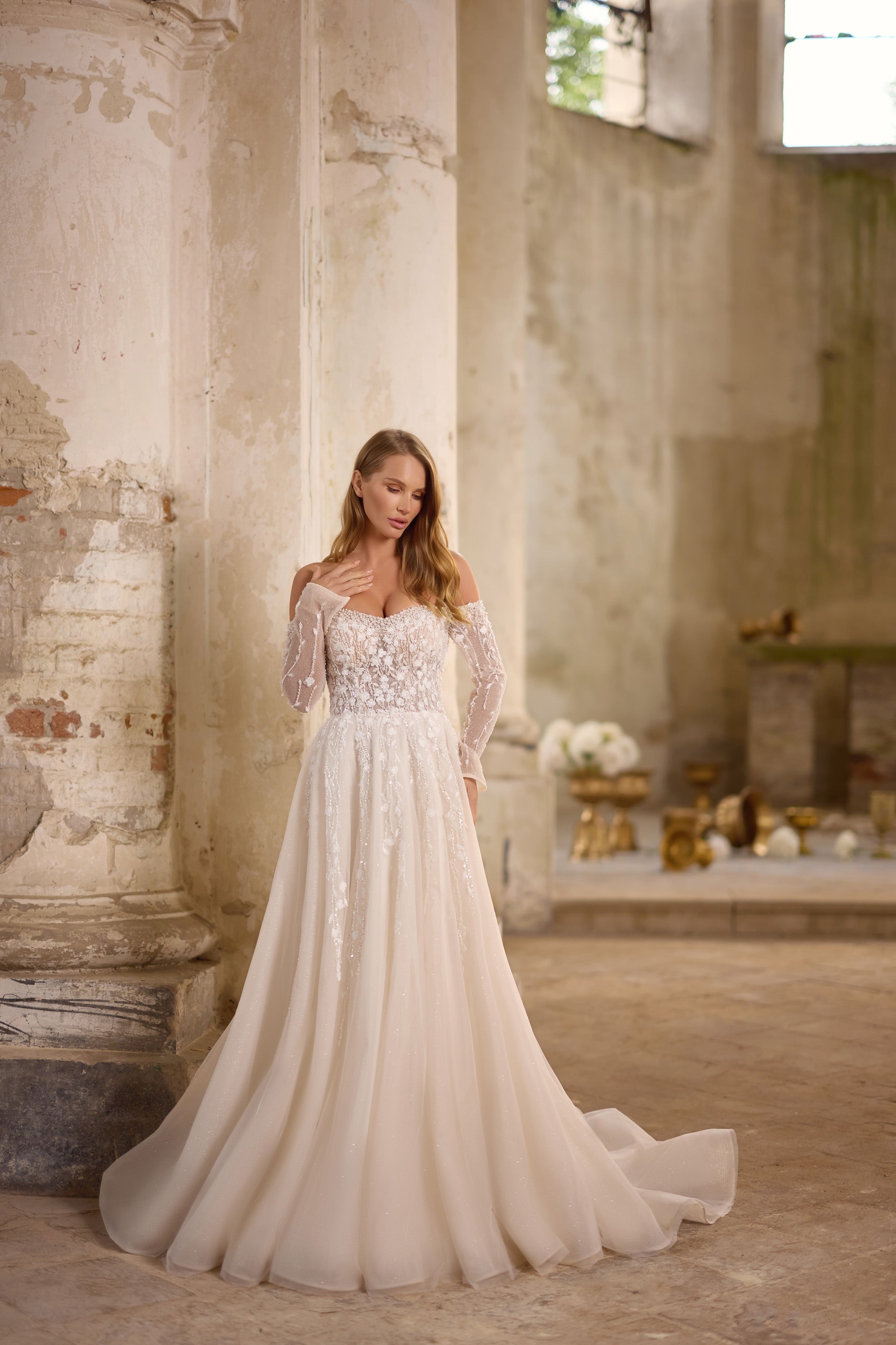 Sparkling ivory A-line wedding dress with a sweetheart neckline, sheer long sleeves, and a sweeping train