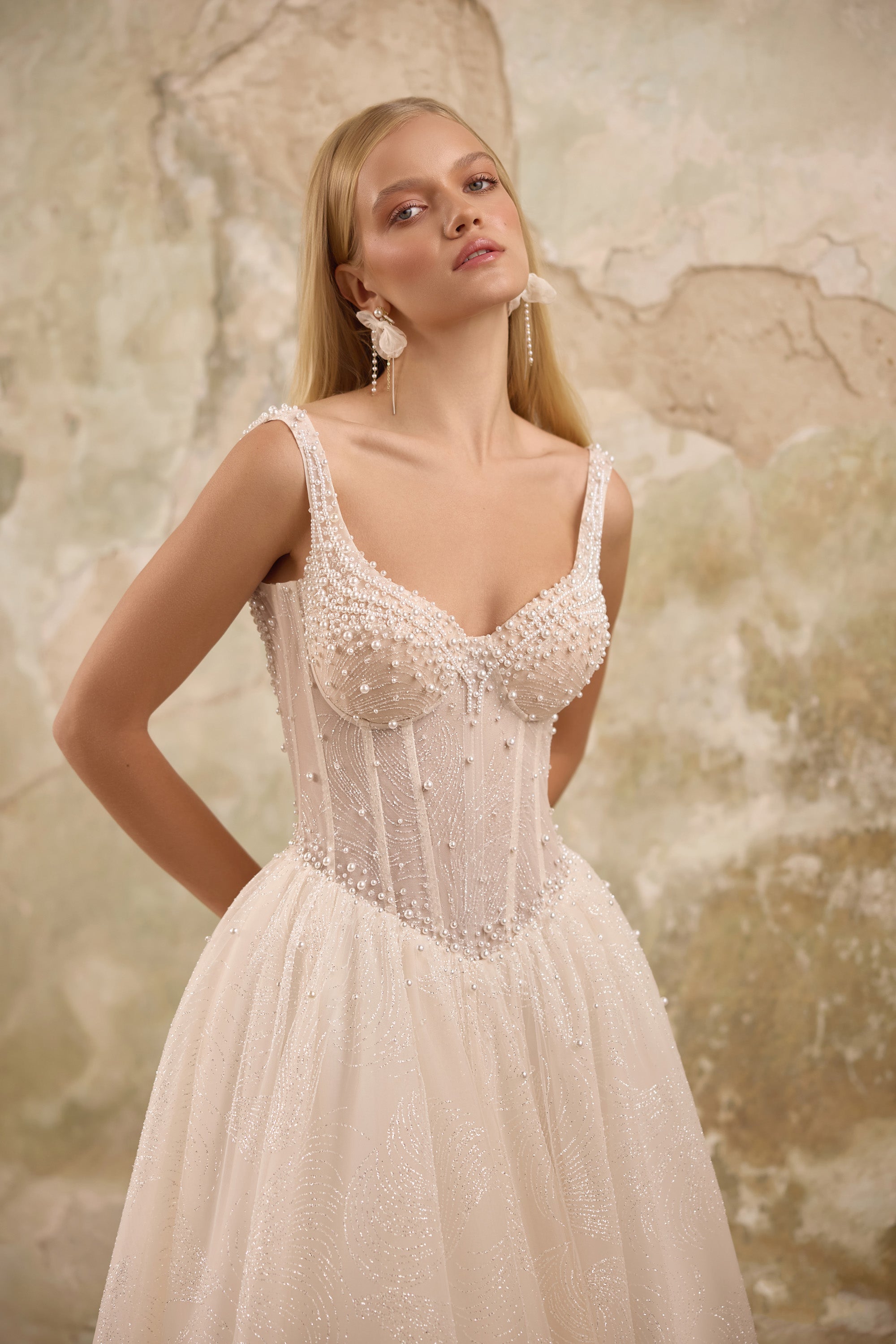 Close-up of pearl beadwork, delicate straps, and a sweetheart bodice on an ivory wedding dress