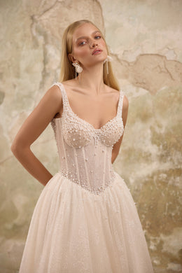 Close-up of pearl beadwork, delicate straps, and a sweetheart bodice on an ivory wedding dress