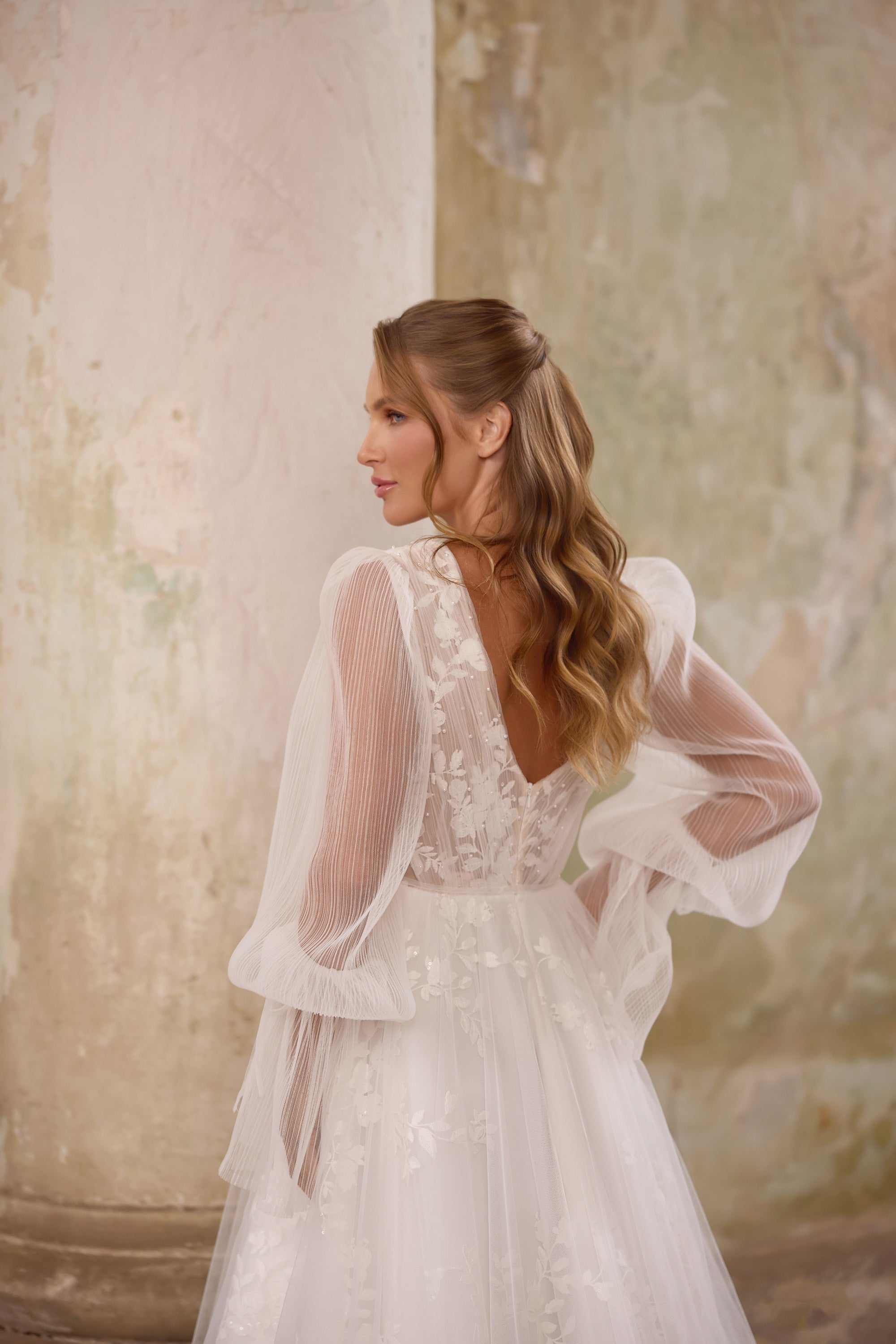 Ivory wedding dress with a lace V-back, sheer bishop sleeves, and an A-line skirt