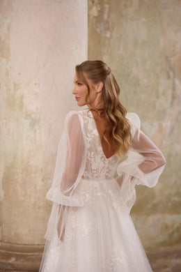 Ivory wedding dress with a lace V-back, sheer bishop sleeves, and an A-line skirt