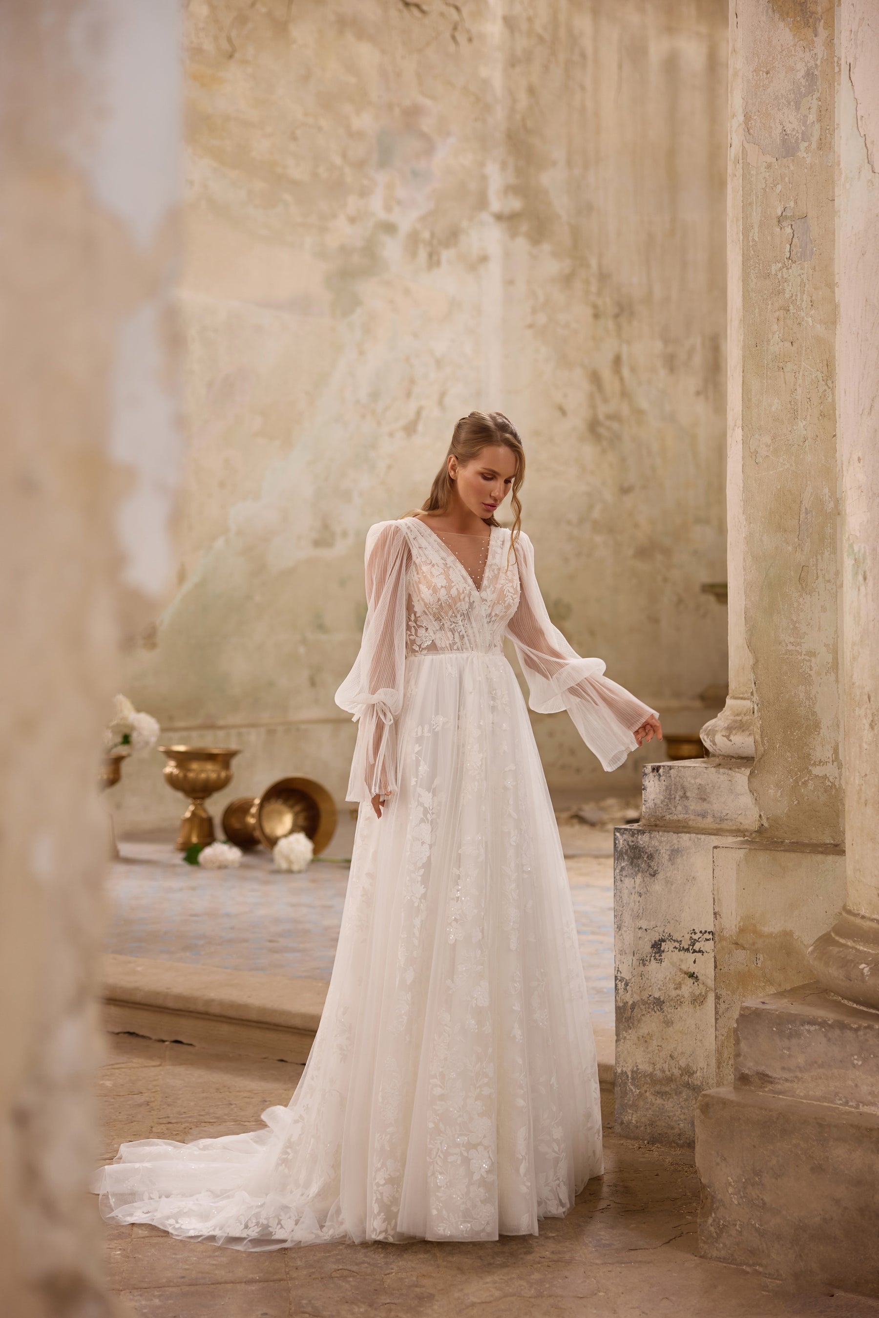 Ivory A-line wedding dress with a plunging V-neckline, lace bodice, bishop sleeves, and train
