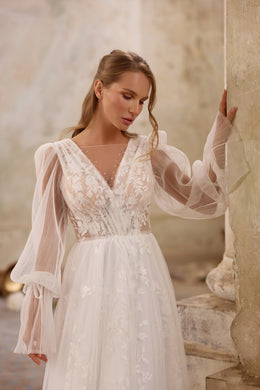 Close-up of floral lace appliqués, sheer V-neck mesh, and bishop sleeves on a wedding dress