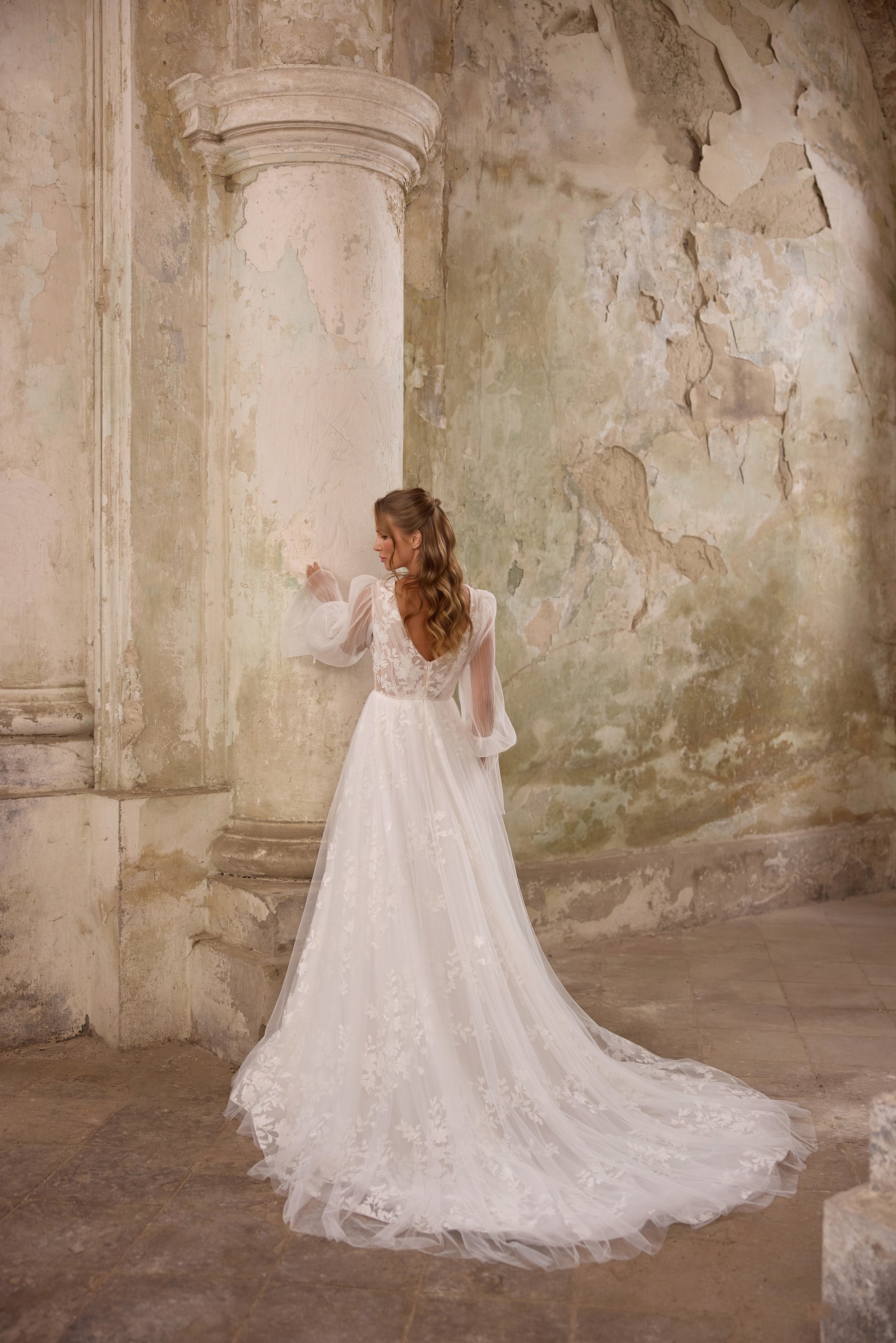 Lace-back ivory wedding dress with sheer sleeves, an A-line silhouette, and a long flowing train