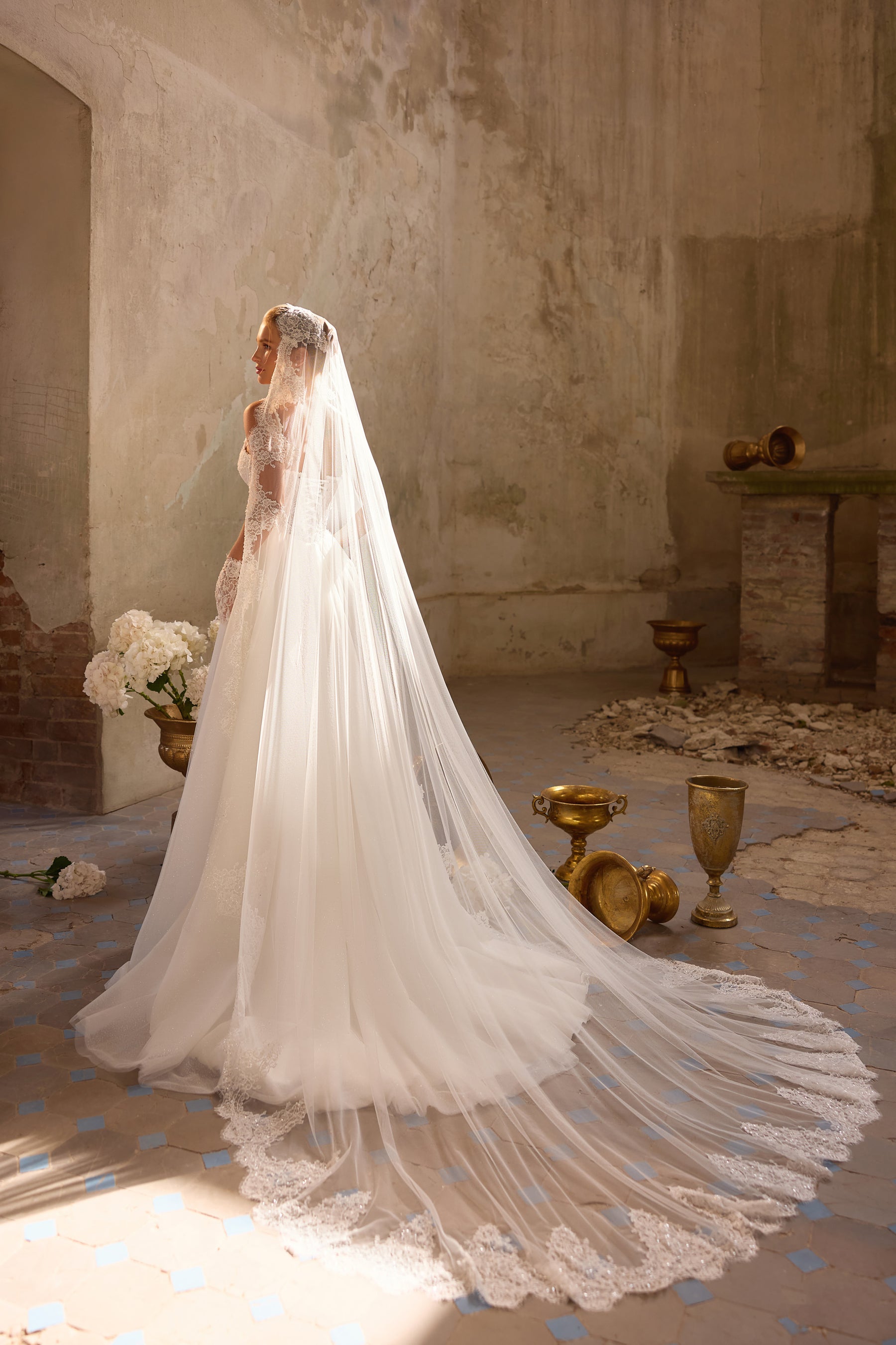 Ivory wedding dress with a long sheer veil, flowing skirt, and scalloped lace train