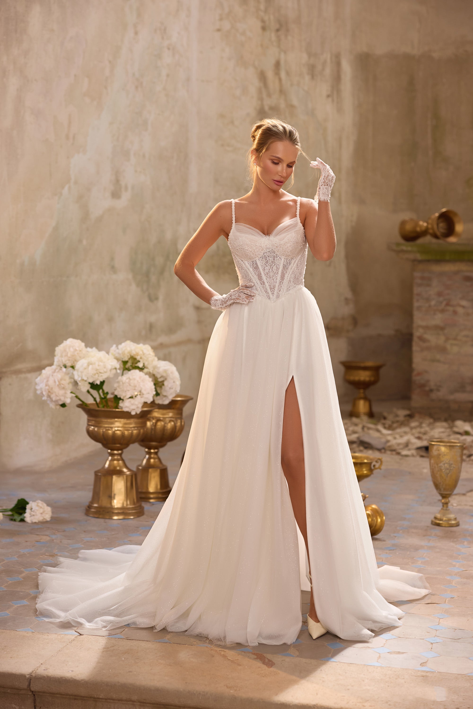 Ivory A-line wedding dress with a lace corset bodice, thin straps, high slit, and train