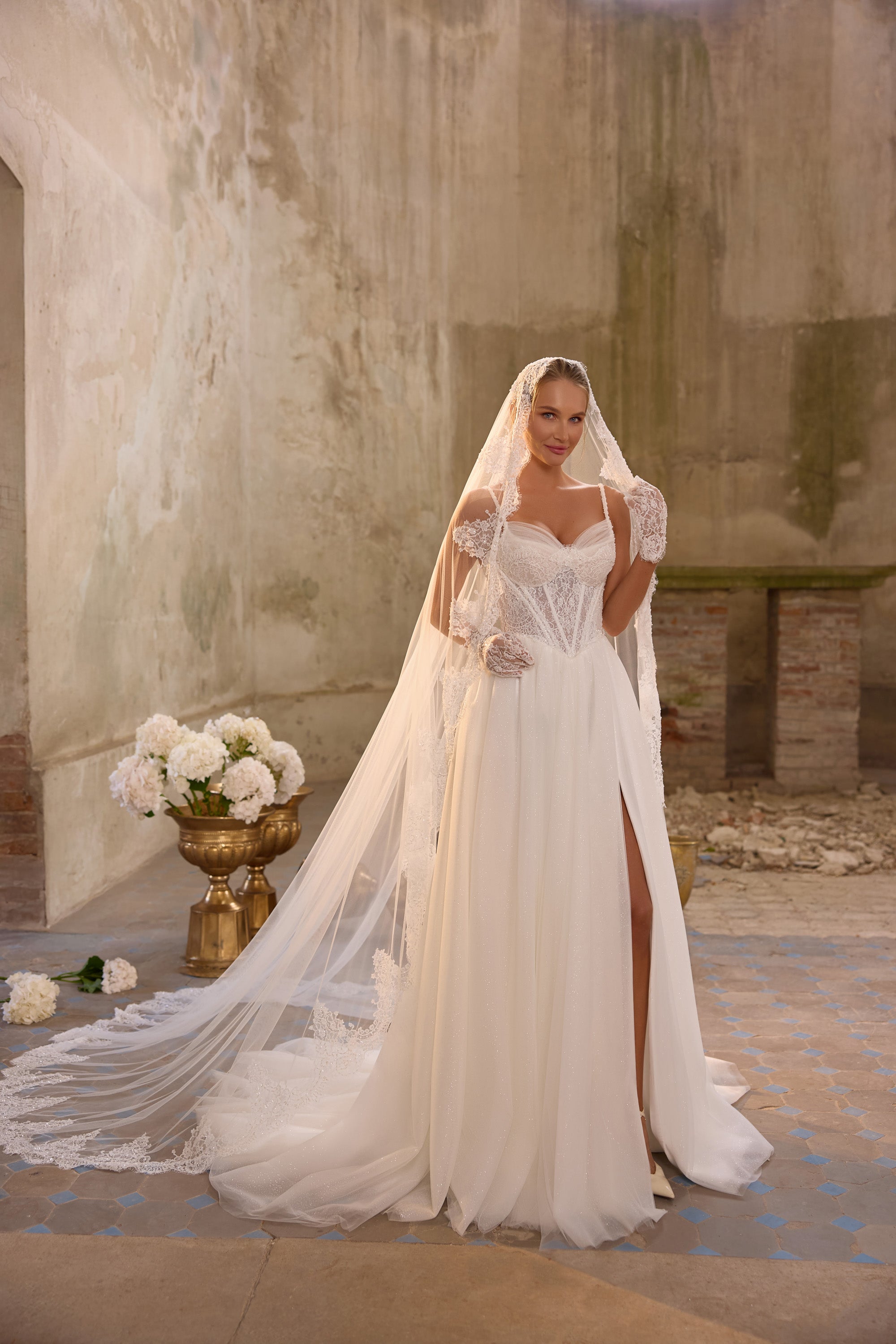 Ivory wedding dress with a lace-trimmed veil, fitted lace bodice, side slit, and sweeping train