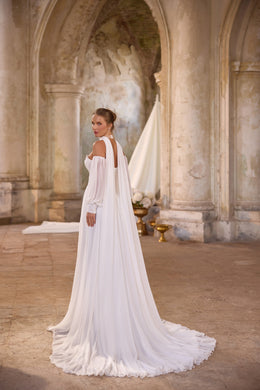 Three-quarter back view of an ivory wedding dress with a flowing detachable cape and long gathered train