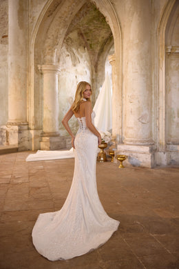 Ivory mermaid wedding dress with a low open back, sparkling lace, and a sweeping train