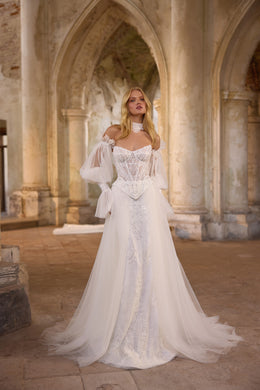 Ivory wedding dress with a beaded sweetheart bodice, sheer puff sleeves, and a flowing overskirt
