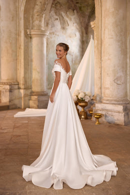 Ivory wedding dress with an off-shoulder neckline, short sleeves, fitted waist, and flowing A-line train
