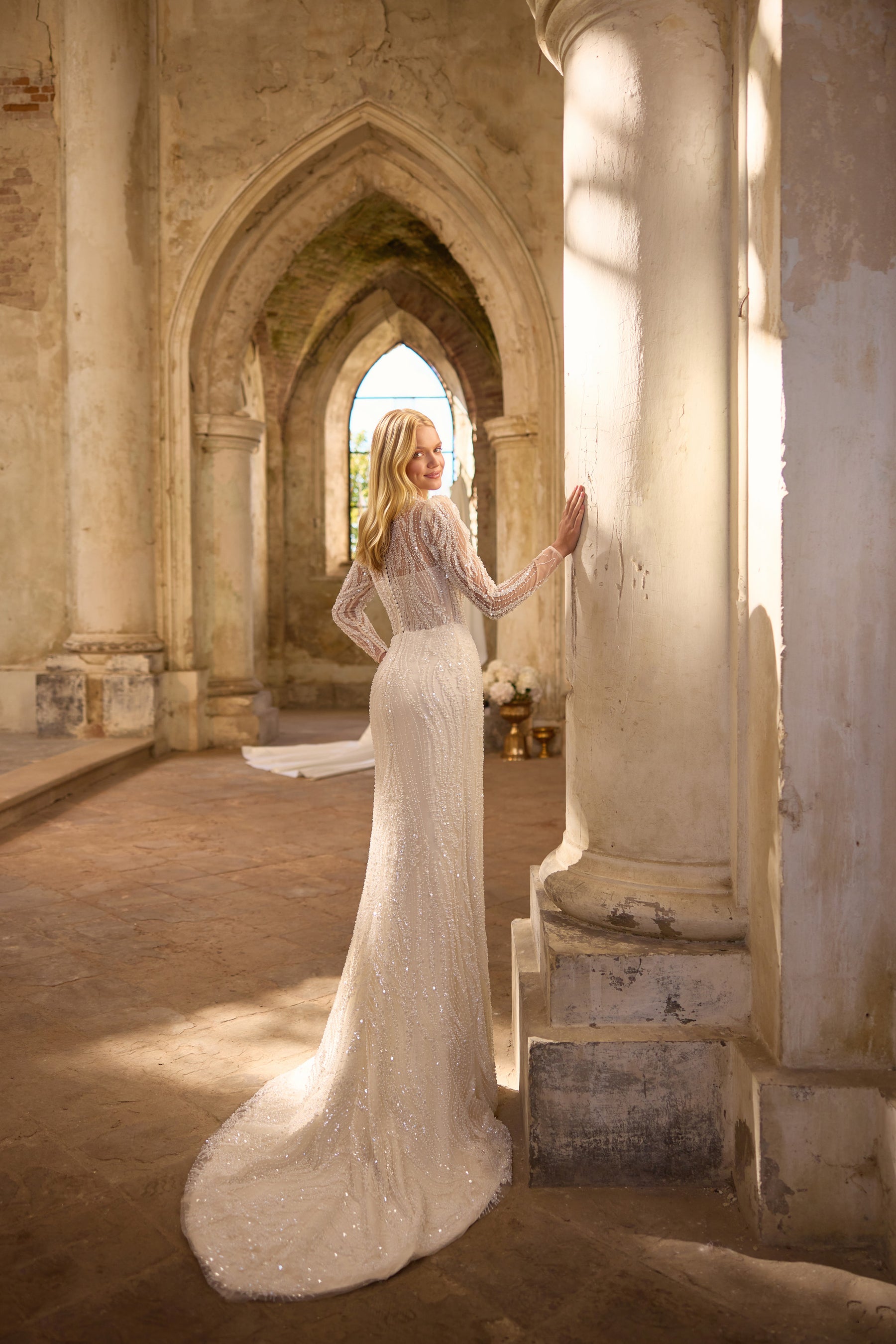 Ivory beaded lace sheath wedding dress with long sleeves, a high neckline, and a sweeping train