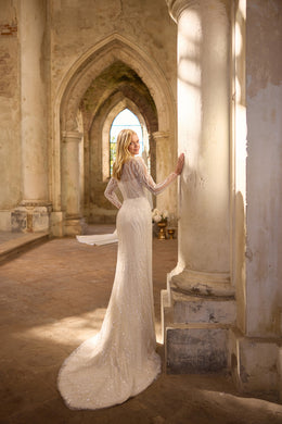 Ivory beaded lace sheath wedding dress with long sleeves, a high neckline, and a sweeping train