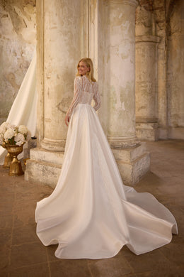 Rear view of an ivory wedding dress with a detachable full overskirt and a wide, flowing train