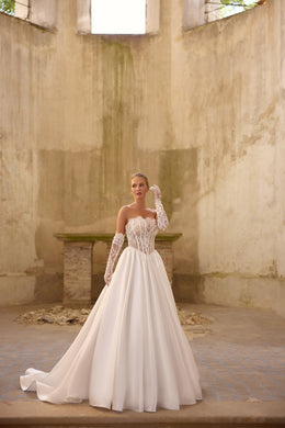 Sweetheart neckline, beaded corset, and full satin skirt on an ivory wedding dress with lace sleeves