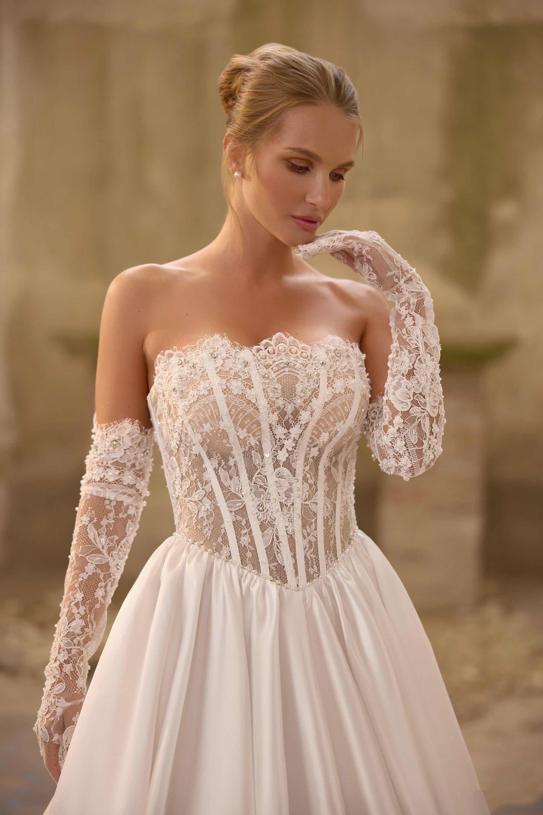 Close-up of floral lace corset and sweetheart neckline on an ivory wedding dress with sheer lace sleeves