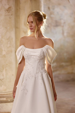 Ivory wedding dress with an off-the-shoulder neckline, draped short sleeves, and floral lace appliqués on the bodice