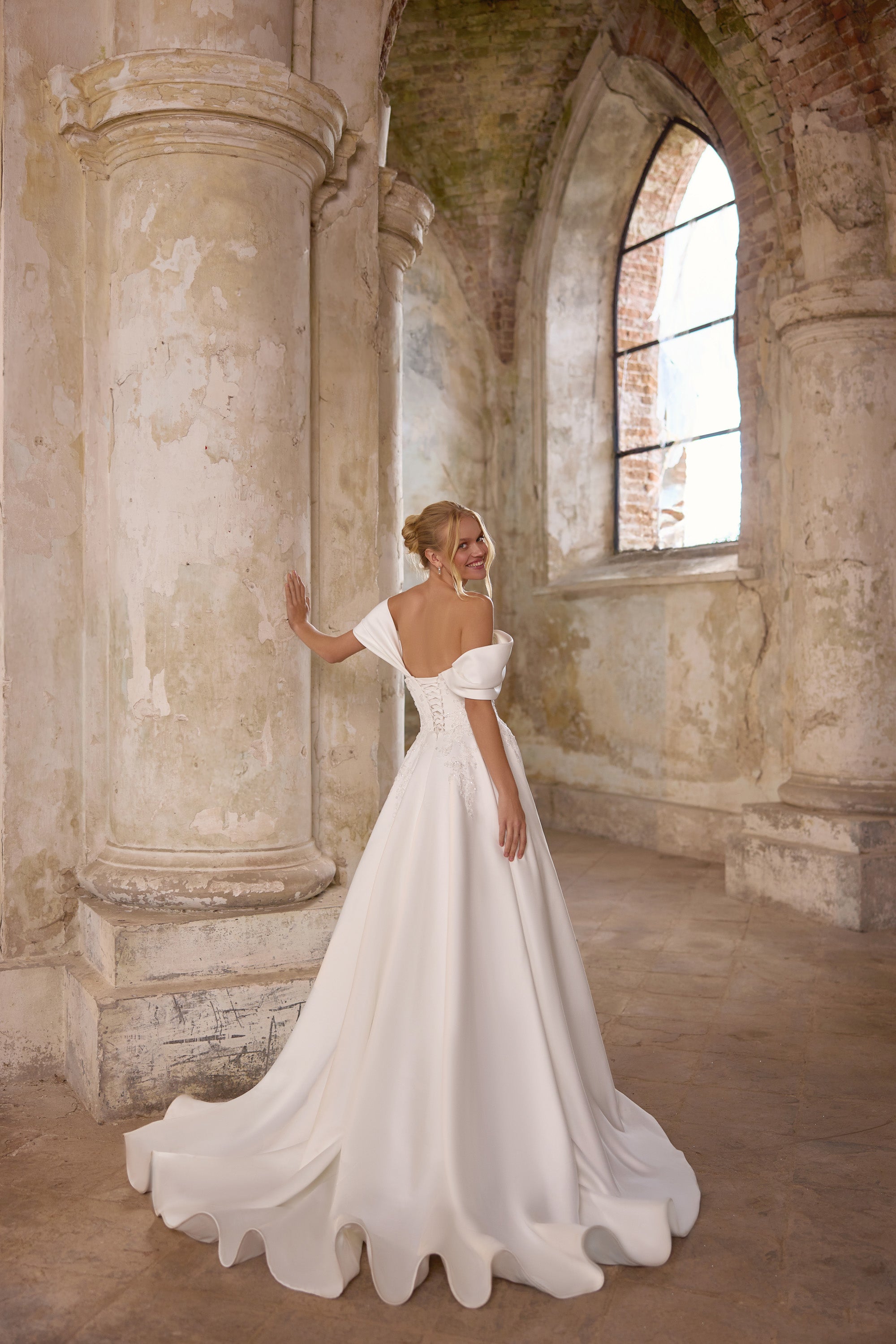 Ivory satin A-line wedding dress with off-the-shoulder sleeves, floral appliqués, and a sweeping train