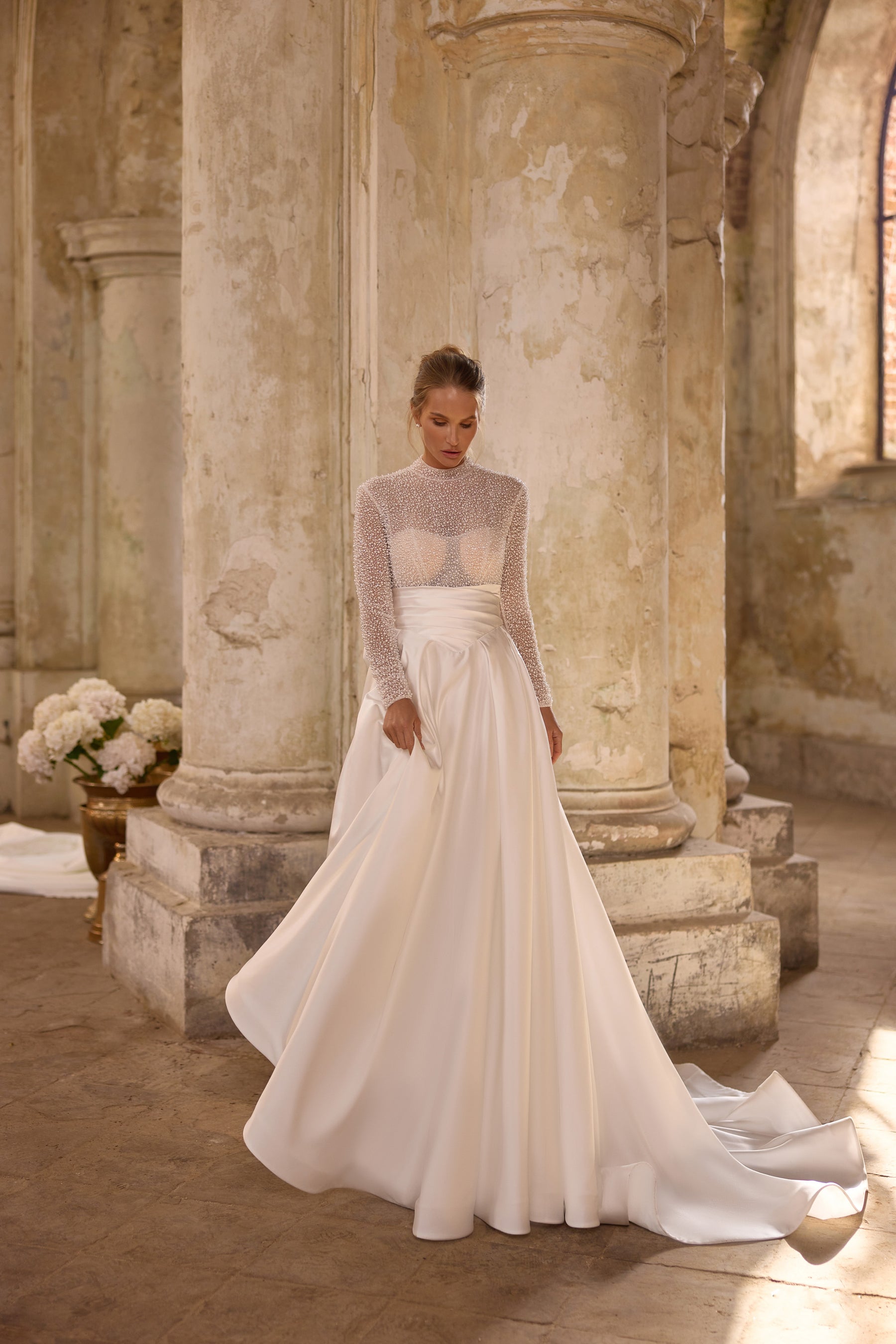 Ivory A-line wedding dress with a beaded high neckline, sheer long sleeves, and sweeping train