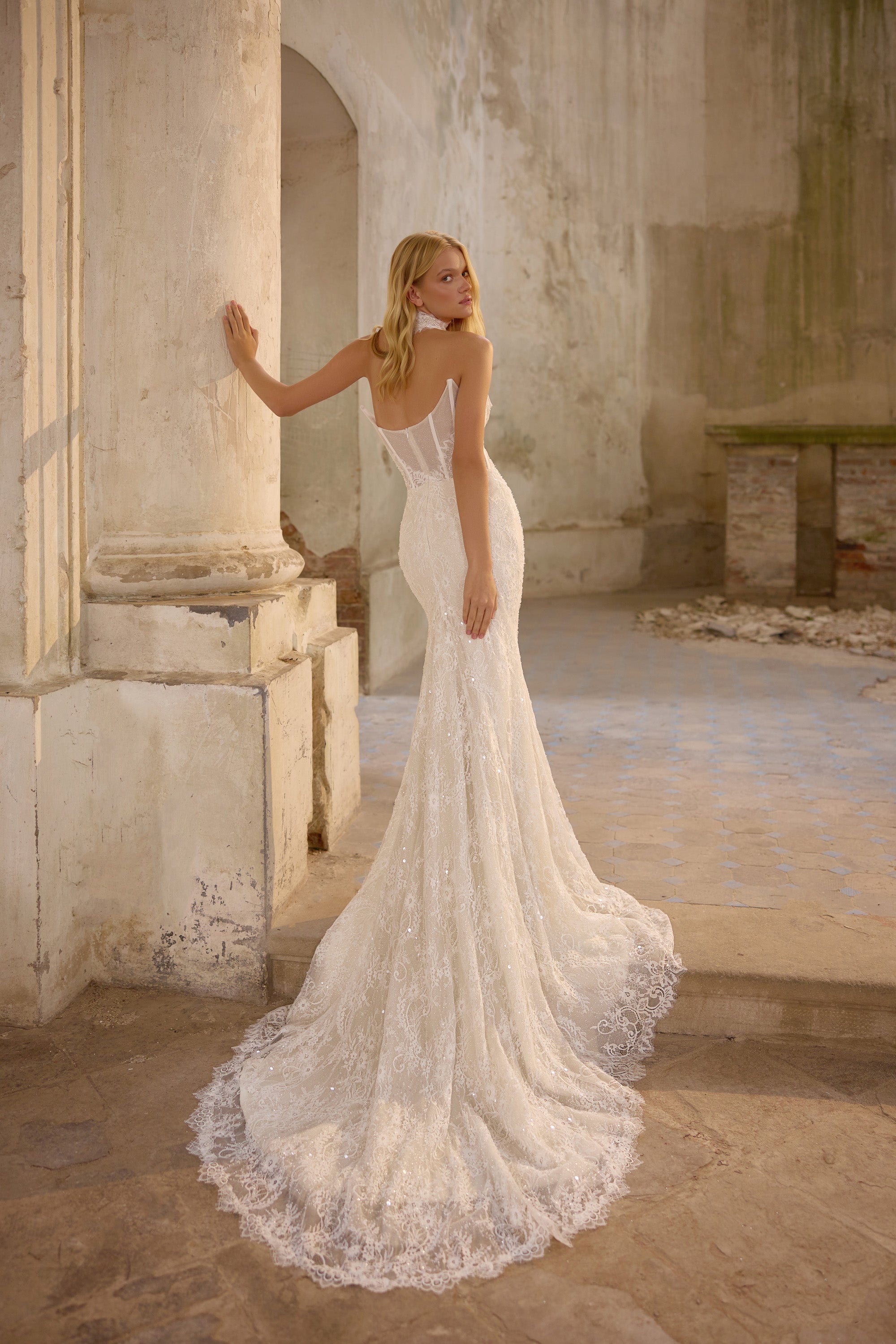 Ivory mermaid wedding dress with an open back, sparkling lace, and a long scalloped train
