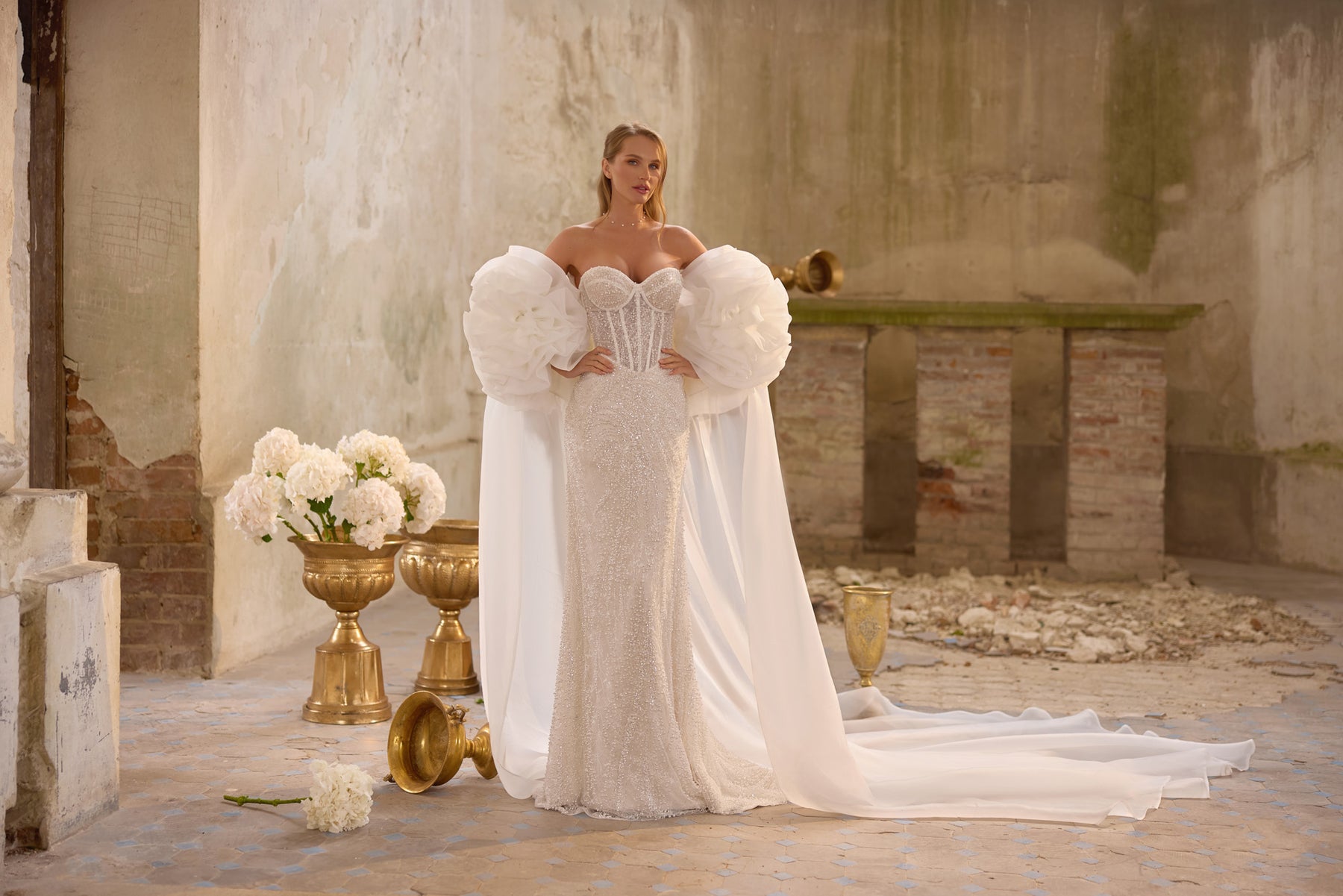 Beaded mermaid wedding dress styled with dramatic puff sleeves and a long flowing cape train