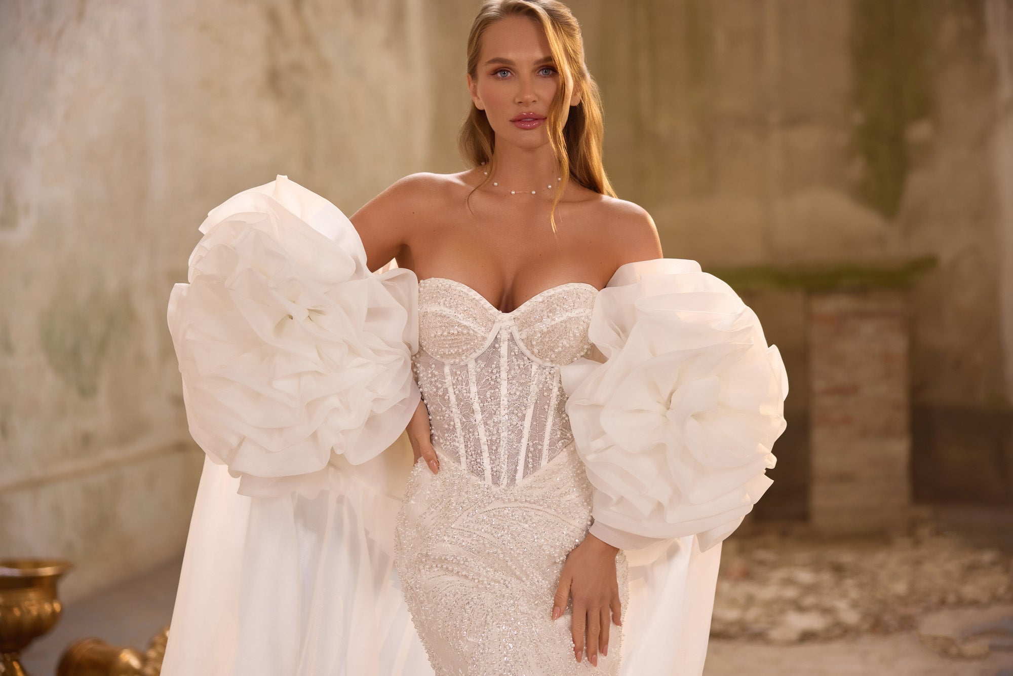 Close-up of a sweetheart wedding dress bodice with structured seams, beadwork, and oversized ruffled sleeves