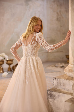 Ivory wedding dress with sheer lace long sleeves, floral back detailing, and a flowing full skirt